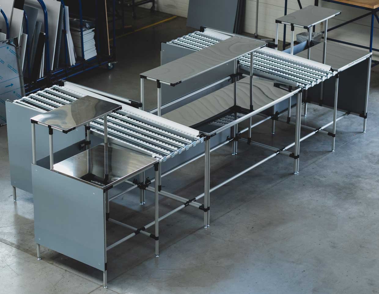 Assembly line with stainless steel-encased work surface and FIFO roller conveyors