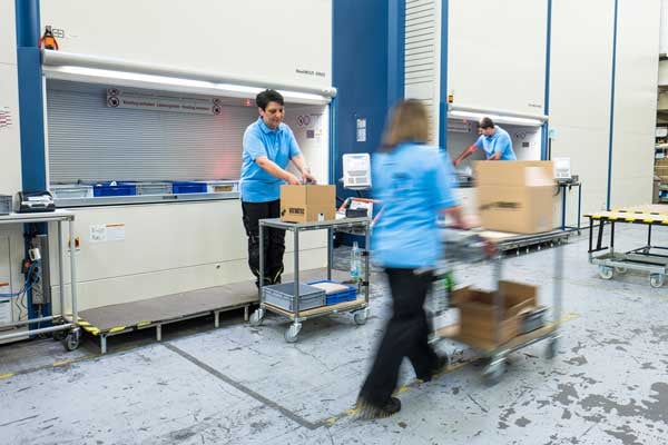 Several people pick items for dispatch at a modern automated vertical storage system.