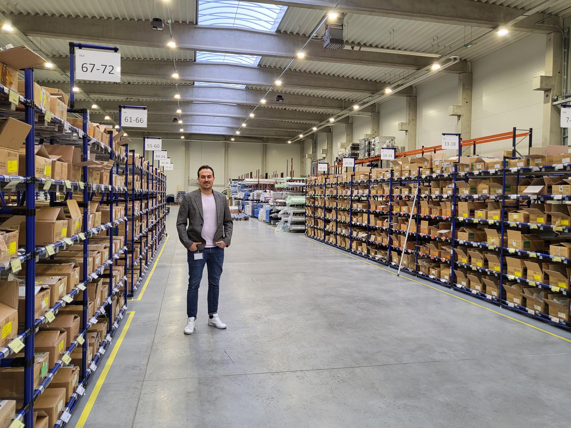 COO Joachim Walter stands in a large warehouse between storage racks.