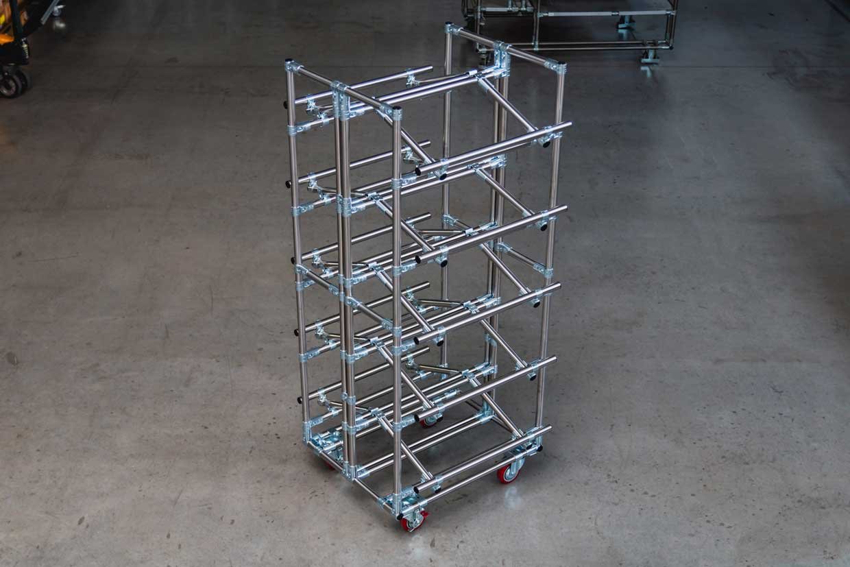 Large movable shelf made of shiny round pipe with four casters with red tread